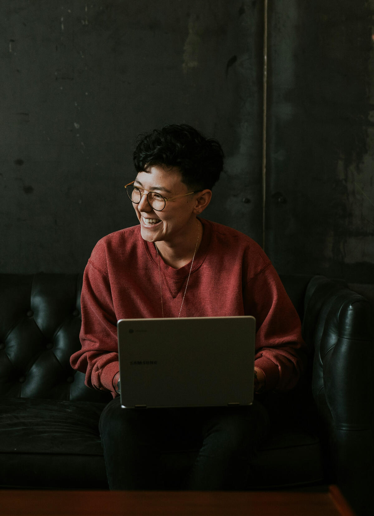 This Is What Reinvention Feels Like Person smiling while working on a laptop in a cozy, modern space — representing confidence and clarity during a career reinvention journey.